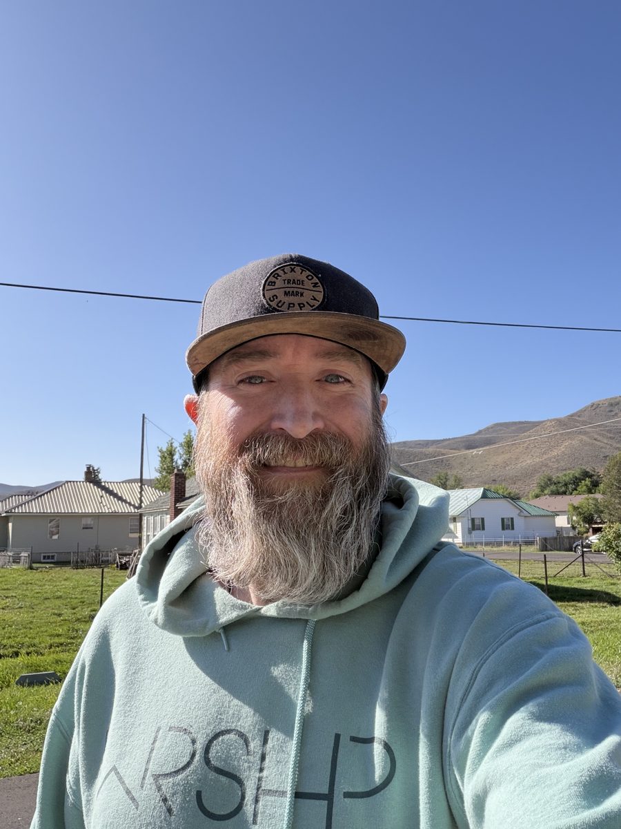Michael smiling outdoors in Utah, wearing a cap and a mint hoodie